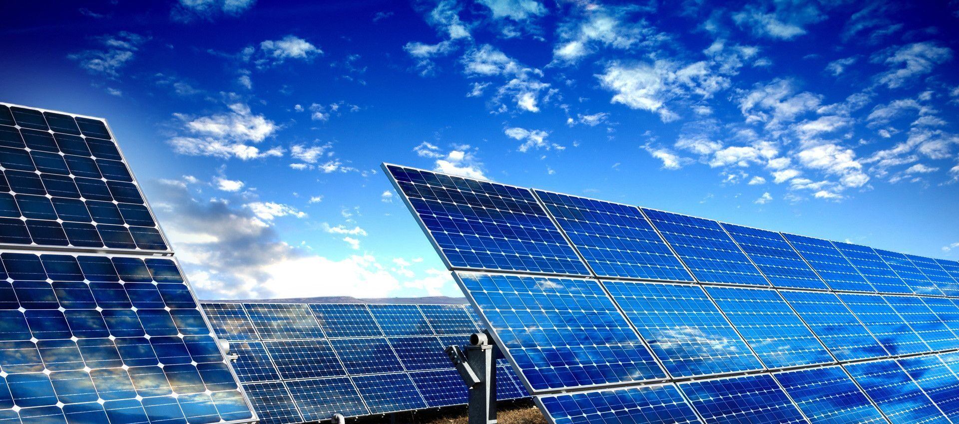 A wide view of solar panels under a vivid blue sky.