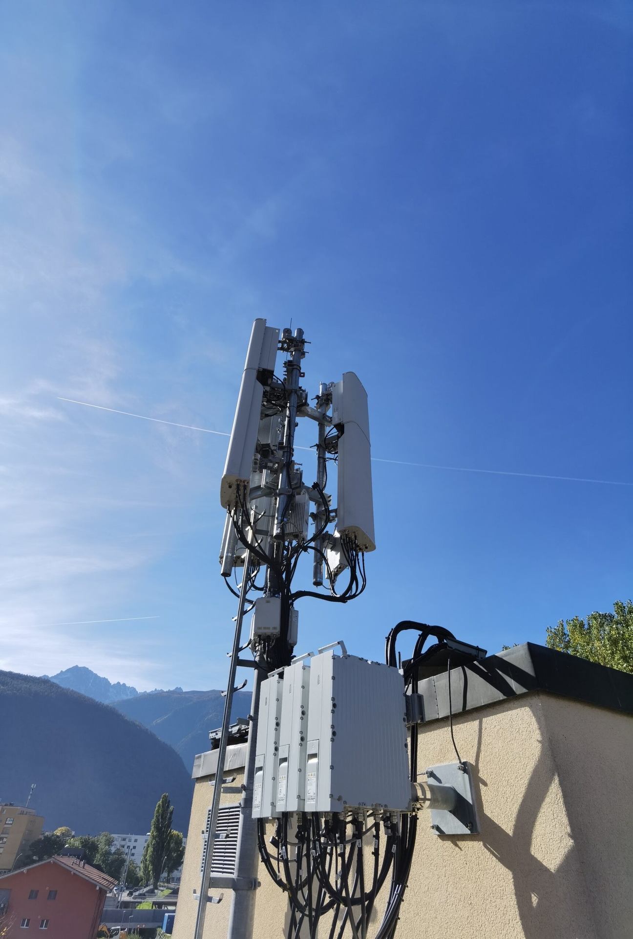 A rooftop antenna mast under a clear blue sky.
