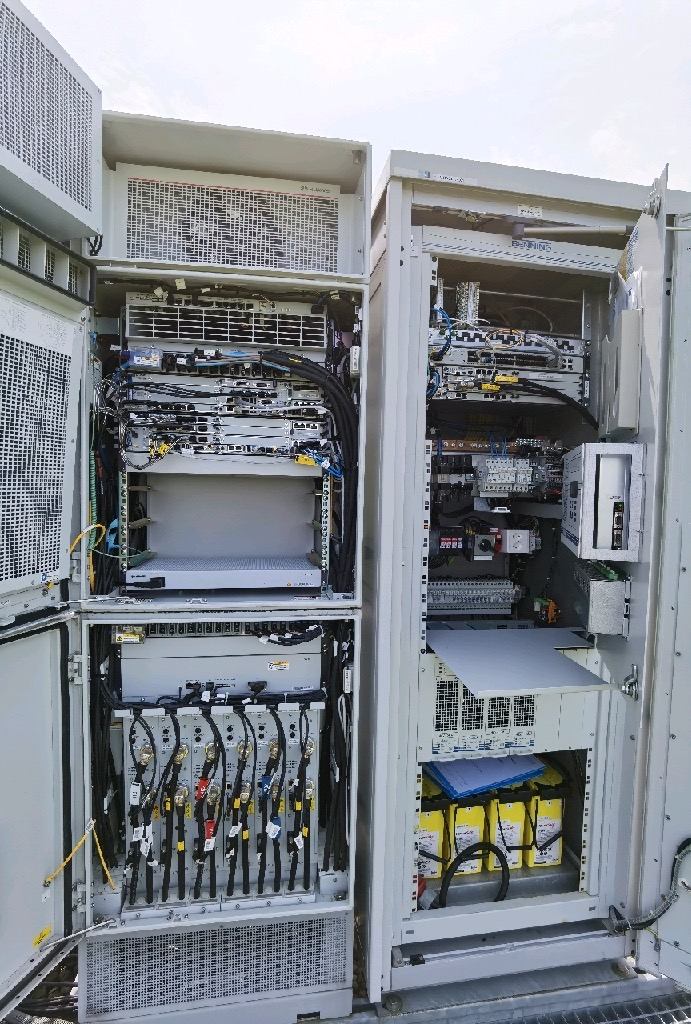 Two open outdoor cabinets with telecommunications units and wiring.