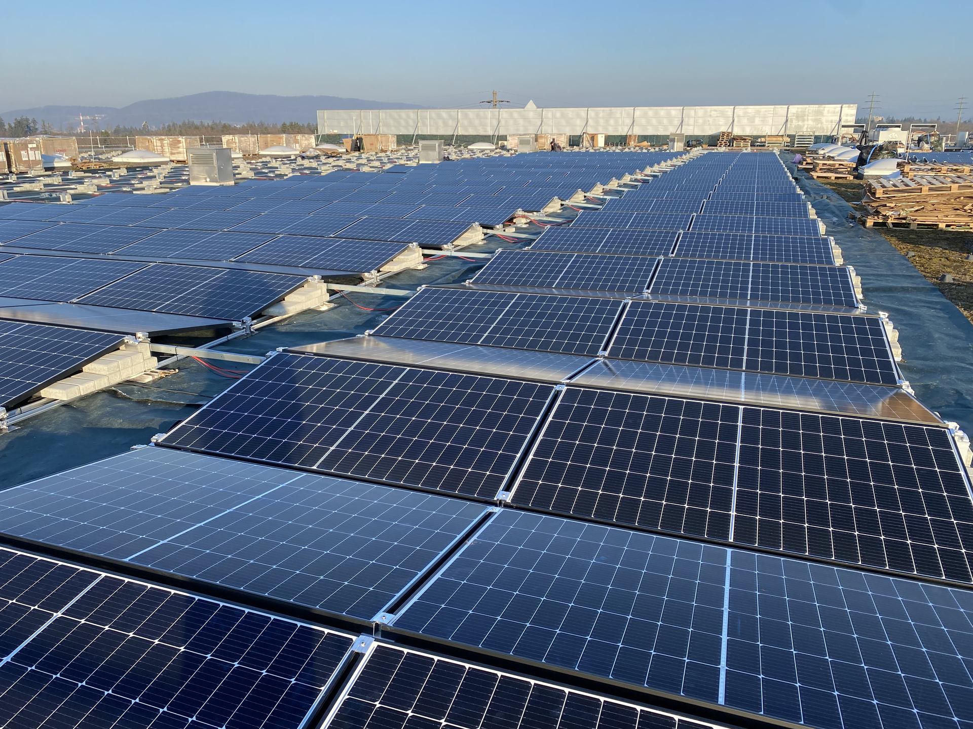 Long rows of photovoltaic panels covering a broad rooftop.