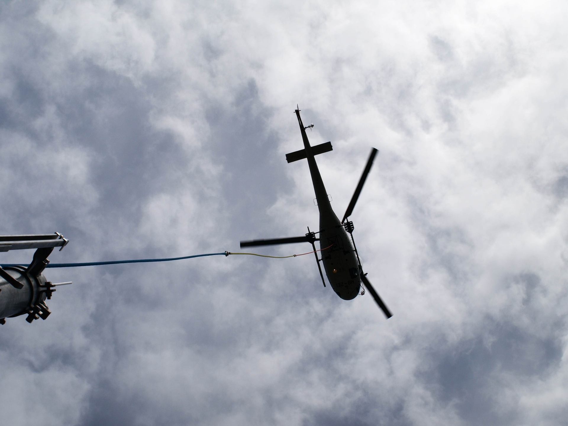 A helicopter silhouetted against a cloudy sky.