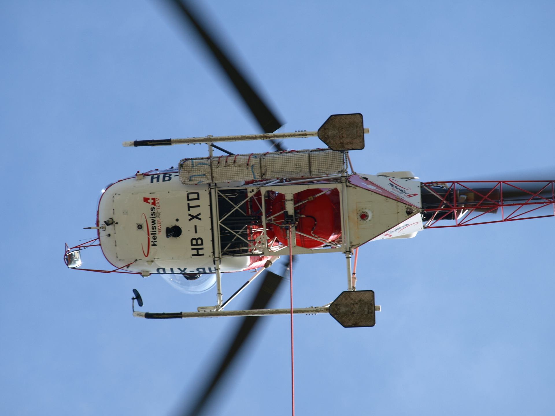 The underside of a helicopter against a clear sky.