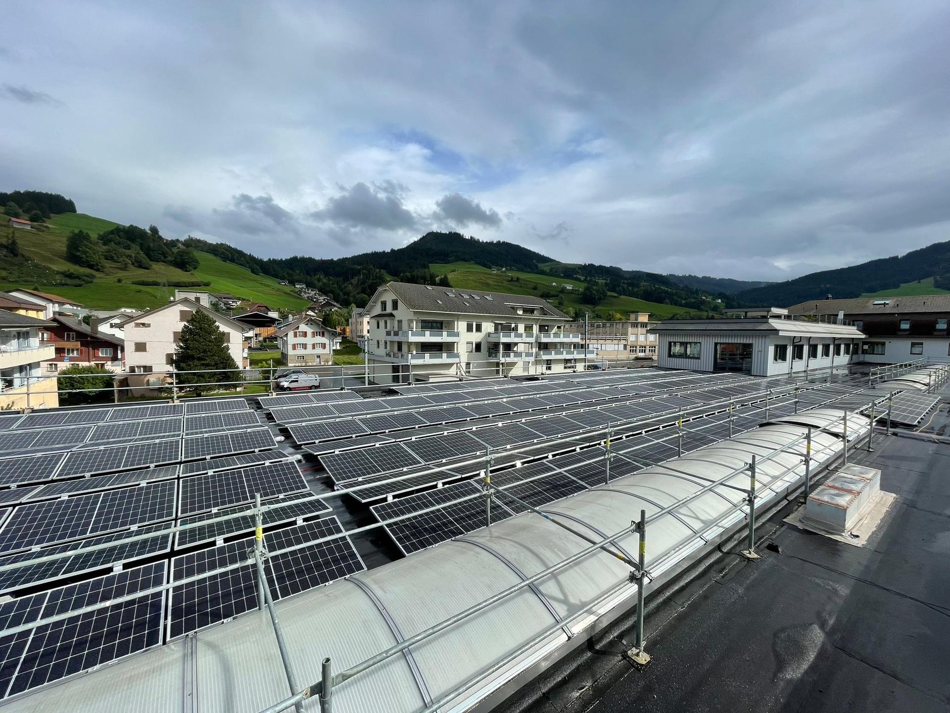 Rows of rooftop photovoltaic panels with hills in the background.