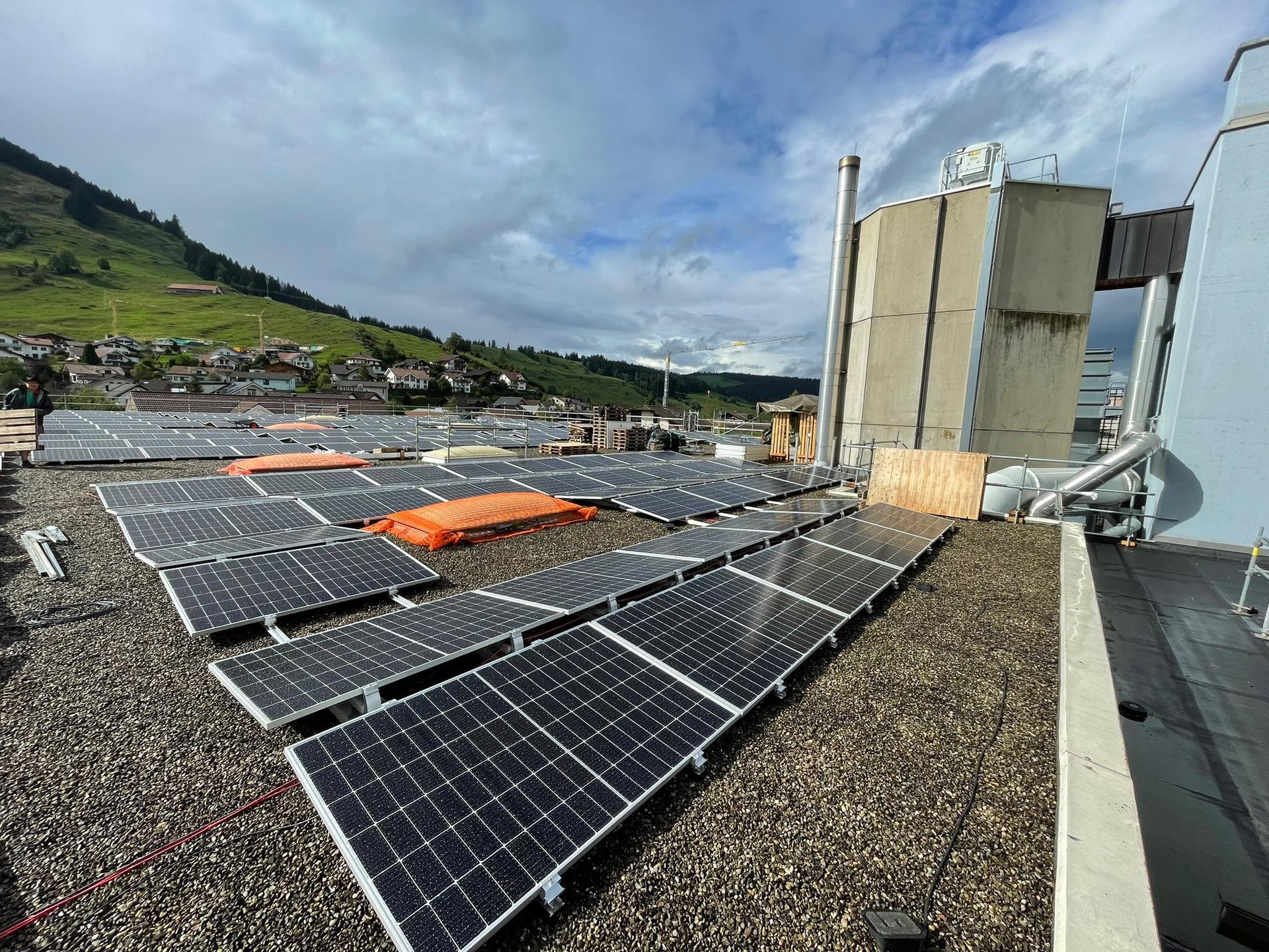 Solar panels beside rooftop equipment on a gravel-covered roof.