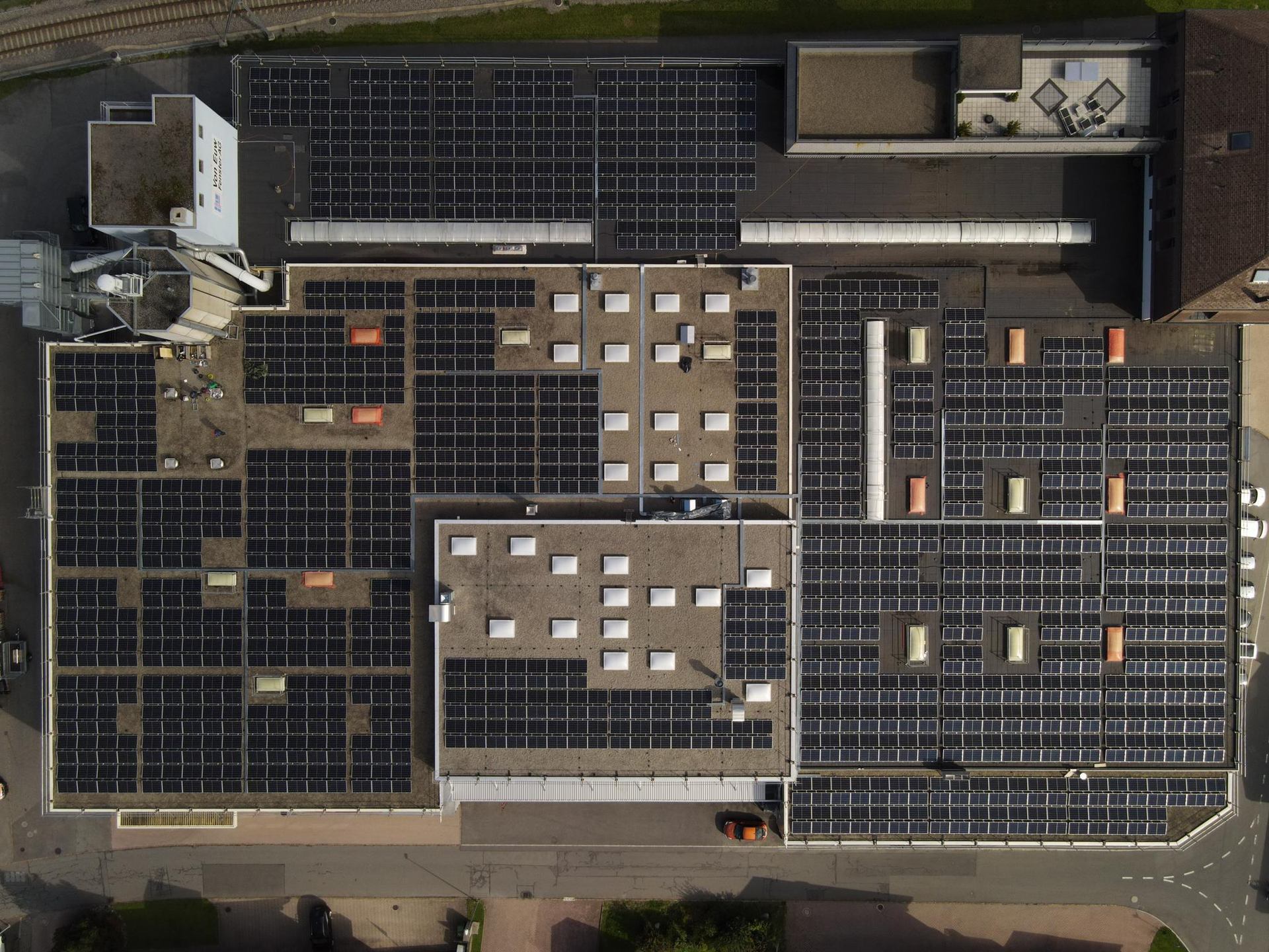 An overhead view of solar arrays arranged across several roof areas.