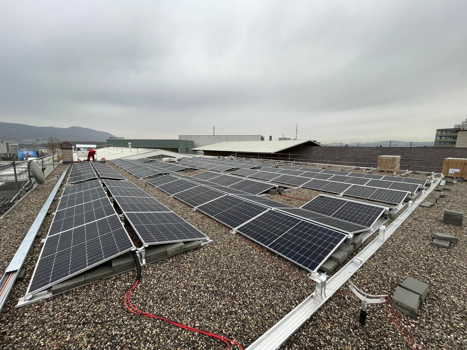 Angled solar modules on a gravel-covered roof.
